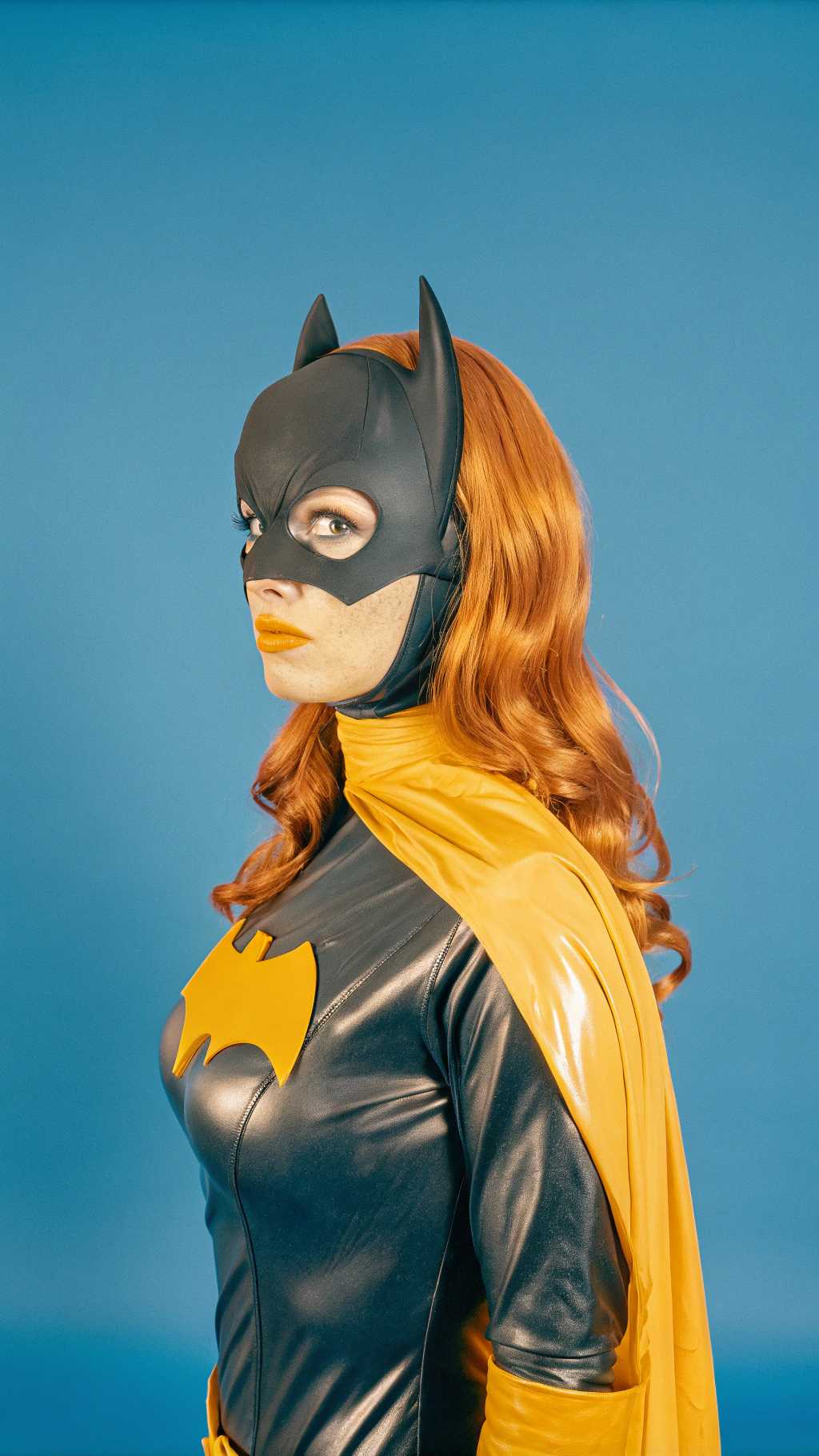 This image is a digital artwork that features a closeup of Batgirl looing at the lens, dressed in a black and yellow costume with a bat emblem, reminiscent of the superhero Batgirl. The character is wearing a sleek, formfitting suit with a high neckline and a cape draped over one shoulder. The suit has a glossy, leatherlike texture, and the emblem is a bright, bold yellow against the black background.The characters hair is a rich, fiery red, styled in long, flowing waves that cascade down the back and over the shoulders. The hair has a realistic sheen and volume, with individual strands that catch the light, giving it a lifelike quality.The art style is highly detailed and realistic, with a focus on textures and lighting that give the image a threedimensional feel. The rendering is smooth and polished, with a high level of detail in the clothing, hair, and skin. The lighting is dramatic, with shadows that accentuate the contours of the character and the folds of the costume.The medium appears to be a 3D rendering, given the smooth surfaces, the way light interacts with the materials, and the subtle reflections and highlights. The use of lighting and shadow adds depth and dimension to the image, making the character and the costume stand out against the dark background.Overall, the image is a striking portrayal of a superheroine, rendered with attention to detail and a cinematic quality that suggests it could be from a comic book, a video game, or a highquality animation.