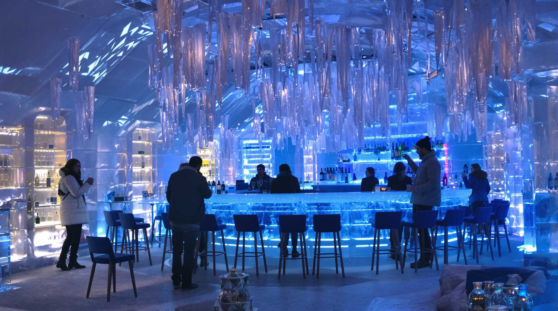 Inside a Bar complete made out of ice in Finnland. Party people in winter dressing enjoy there drinks. Crystal clear atmosphere with transparent ice bar in background illuminated with blue led lighting 