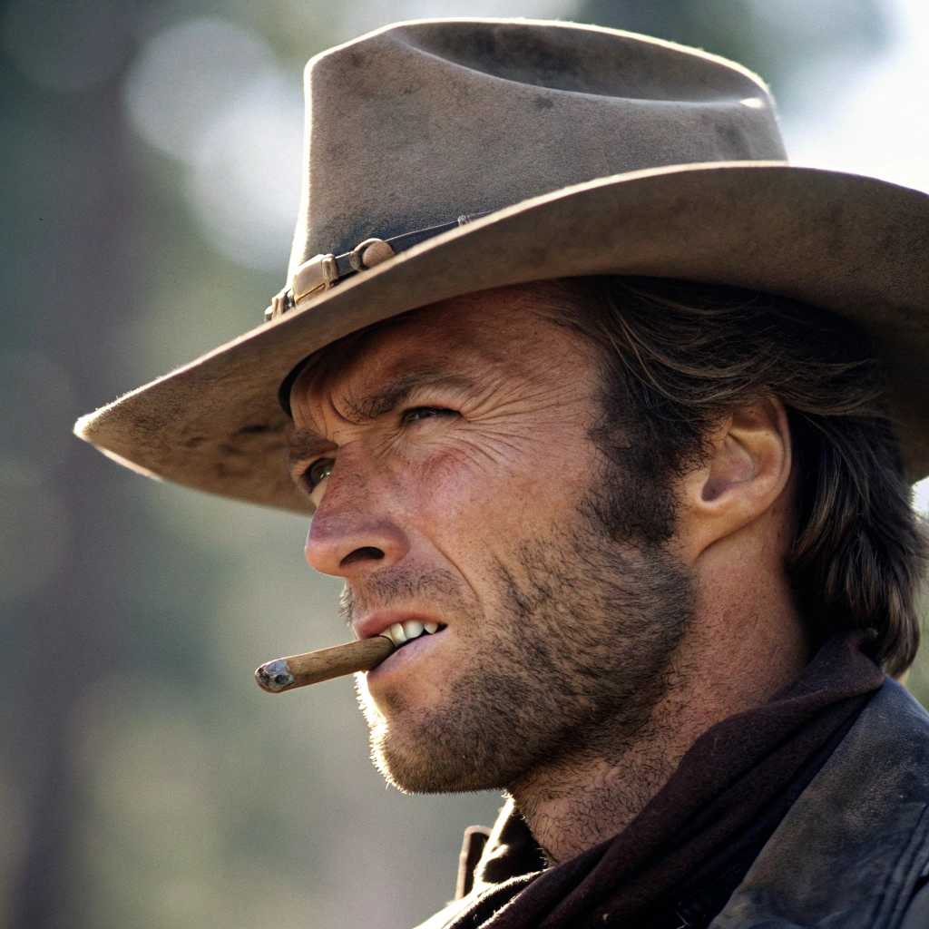 Face closeup of Clint Eastwood with cigar in mouth and cowboy hat, bokeh
