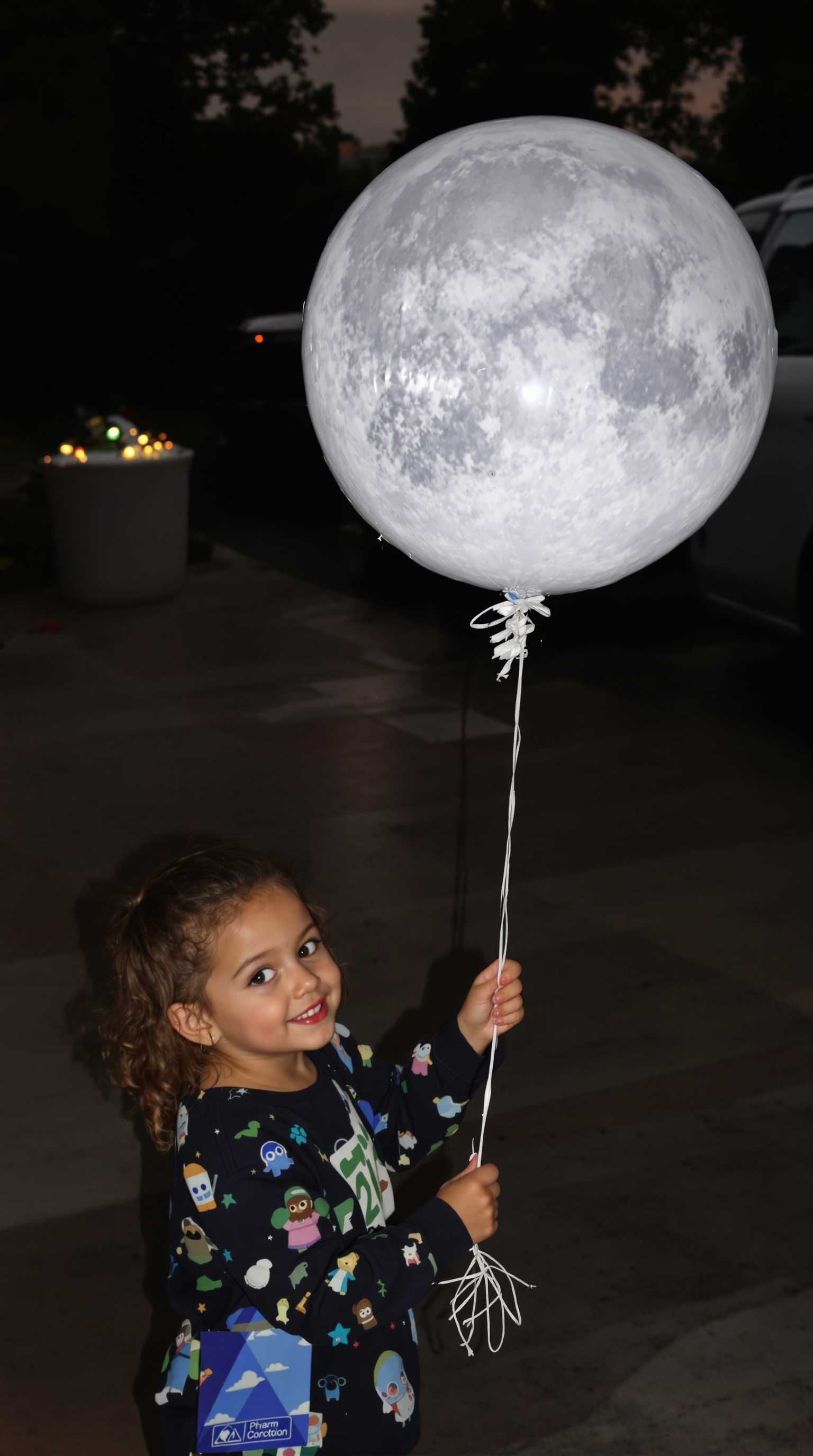 A child holding a balloon shaped like a moon