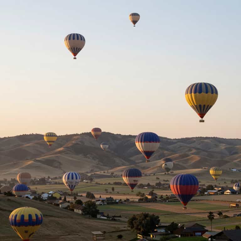 Balloons Ascending Over Golden Hills