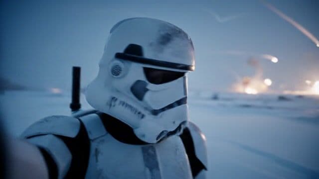 A cinematic handheld selfie-style medium shot, set on a snowy battlefield at dusk. A stormtrooper in full white armor holds the camera at arm’s length, his helmeted face perfectly framed as snowflakes swirl gently in the cold air. His armor is lightly dusted with frost and ash. Behind him, a vast frozen landscape stretches into a shallow-focus blur—explosions flicker in the distance, and streaks of missile trails arc across the twilight sky.

The stormtrooper slowly pans the camera sideways, revealing another stormtrooper crouched in the snow, carefully sculpting a snowman with exaggerated focus. Bits of snow cling to his gloved hands and leg plates as he works.

Back on camera, the first stormtrooper yells with a sense of urgency:
“Okay so we’re in the middle of launching Social AF dot AI, people are screaming, and Roman’s building a darn snowman.”