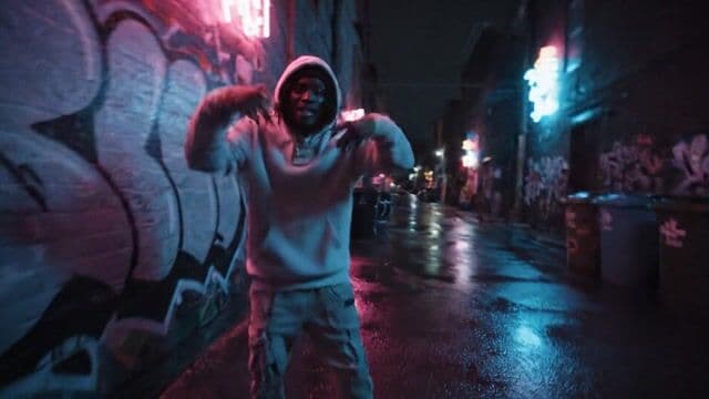{
  "subject": "a confident male hip-hop artist with dreadlocks, wearing a streetwear outfit with oversized hoodie, cargo pants, chunky sneakers, and layered gold chains",
  "pose": "leaning casually against a graffiti-covered wall, rapping with expressive hand gestures",
  "environment": "urban alleyway at night with glowing neon signs in pink and cyan, slick wet pavement reflecting the lights, trash bins and graffiti around",
  "camera": {
    "motion": "handheld glide with subtle orbiting movement",
    "focus": "locked on artist’s face and upper body, deep shadows in background",
    "angle": "eye level with slight tilt for dynamic framing",
    "simulation": "RED Komodo 6K with anamorphic lens"
  },
  "lighting": {
    "type": "urban neon lighting",
    "colors": ["pink", "cyan", "electric blue"],
    "intensity": "moody and stylized with rim and fill light effects",
    "mood": "gritty, cinematic, and energetic"
  },
  "mood": "urban confidence, underground rhythm, stylish edge",
  "details": {
    "face": "realistic with detailed textures, sweat glisten, expressive eyes",
    "body": "athletic build in relaxed posture",
    "makeup": "natural skin with shine from street lighting",
    "hair": "tight dreadlocks under a beanie or hood"
  },
  "audio_cues": {
    "vocals": "fast-paced rhythmic rap with confident tone",
    "instrumentals": "deep bass beats, trap percussion, ambient city background noise"
  },
  "render_style": "cinematic hip-hop video aesthetic, photorealistic with lens flares, stylized neon reflections",
  "meta_tokens": [
    "hyperrealistic",
    "neon noir",
    "urban grime",
    "wet asphalt reflections",
    "street lens flares",
    "cinematic LUT",
    "graffiti texture",
    "trap beat mood"
  ],
  "lens_type": "35mm anamorphic with oval bokeh",
  "image_format": "21:9 ultrawide",
  "file_signature": "STILL_808_RED.RAW"
}