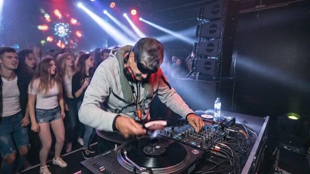 A di is spinning a crazy edm dance beat in a club