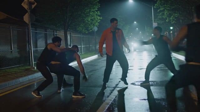 Sudden street fight. Punches thrown, main character knocks down one attacker. Friends fight nearby. Camera: shaky handheld, slow-motion on key hits, cinematic impact shots. Night, wet pavement reflecting street lights. Mood: chaotic, gritty, intense.
