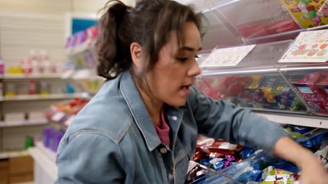 A realistic scene of a woman in a candy store frantically searching to find the last pixel dojo candy bar. once she finds it she exclaims, "gotta have that pixel dojo candy". the candy features a pixelated purple dragon with the text "pixel dojo" on the wrapper.