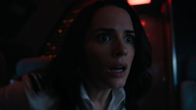 fast action movie scene, hand-held camera, the woman notices the pilots have disappeared and races to take control of the plane, cut to outside shot showing her inside the cockpit at the controls