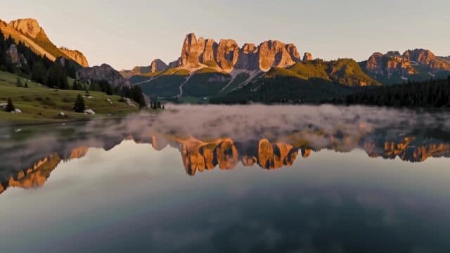 a serene mountain lake at sunrise, slow cinematic push-in, mist rising off the water