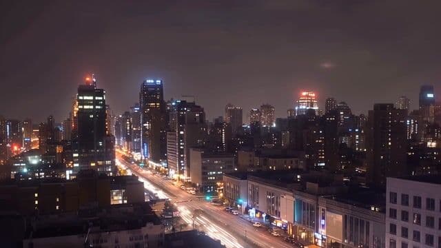 a city skyline at night with glowing lights and gentle traffic, slow cinematic pan