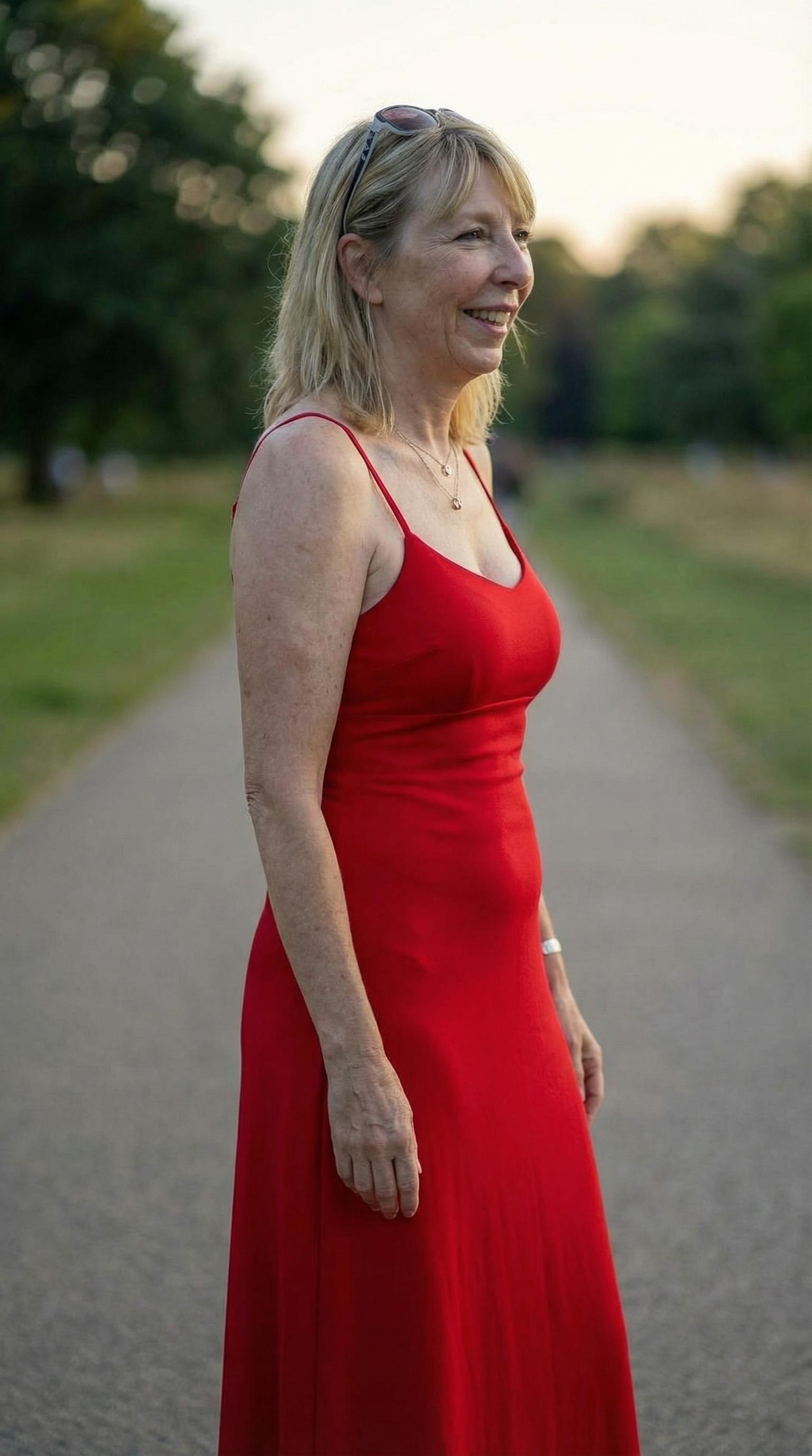 show me this person wearing a red evening dress facing to the right.Make her breasts larger and more prominent. (edited with Google Nano Banana Pro)