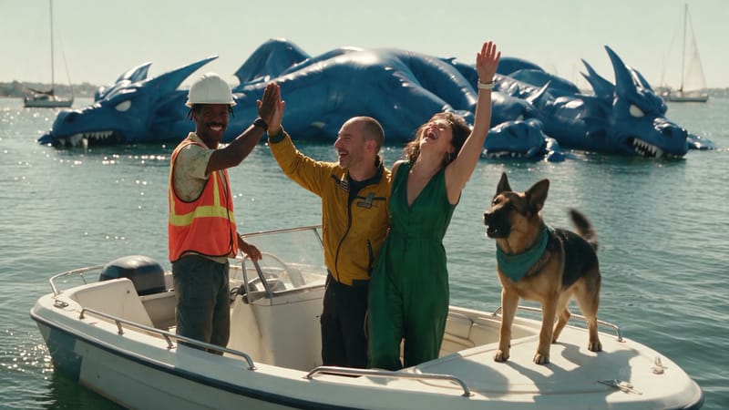 Theo, Brian, Pamela and Circe celebrate on a speedboat, the deflated three-headed dragon floating behind them.