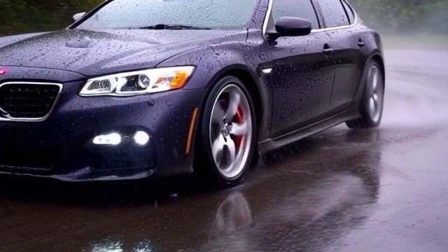 the ultra-wide-angle lens follows closely from the hood, with raindrops continuously splattering
against the lens. Ahead, a sports car speeds around a corner, its tires violently skidding against the wet road,
creating a mist of water. Neon lights refract in the rain, leaving colorful streaks on the car’s surface. The camera
swiftly shifts to the side of the car, capturing the wheels spinning at high speed, before finally moving to the rear