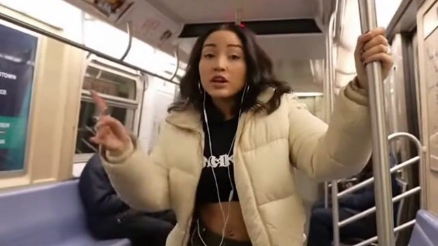 a white woman with black hair rapping on the subway