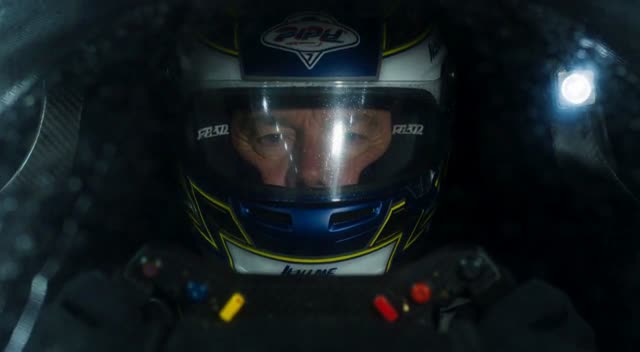 Style: Hollywood Professional Racing Movie (Le Mans Style), Cinematic Night, Rain, High Stakes Sport.
Duration: 15s.

[00-05s] Shot 1: The Veteran (Interior/Close-up).
Rain lashes the windshield of a high-tech race car on a track. The Veteran driver (in helmet) looks over, calm and focused. Dashboard lights reflect on his visor.
Dialogue Cue: He gives a subtle nod and mouths "Let's go."

[05-10s] Shot 2: The Challenger (Interior/Close-up).
Cut to the rival car next to him. The younger driver grips the wheel tight, breathing heavily. Eyes wide with adrenaline.
Dialogue Cue: He whispers "Focus" to himself.

[10-15s] Shot 3: The Green Light (Wide Action).
The starting lights turn Green. Both cars accelerate in perfect sync on the wet asphalt. Water sprays massively into the camera lens. Motion blur turns the stadium lights into long streaks of color.