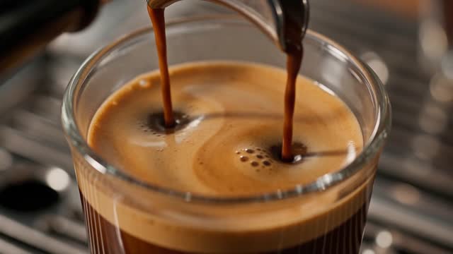 [0-5s] Overhead shot of espresso pulling into a clear glass, crema blooming in slow motion. [5-10s] The camera tilts up as a barista slides the cup across a walnut counter into a shaft of morning light. Warm, tactile, commercial-grade. Audio: grinder, steam hiss, ceramic on wood.
