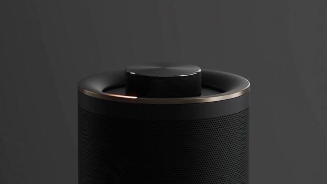 Product spot: a matte-black wireless speaker rotates on a seamless charcoal backdrop as rim lights sweep across its knurled dial. Reflections travel the metal edge. Crisp studio key, controlled specular highlights. Audio: a clean low bass note blooming.