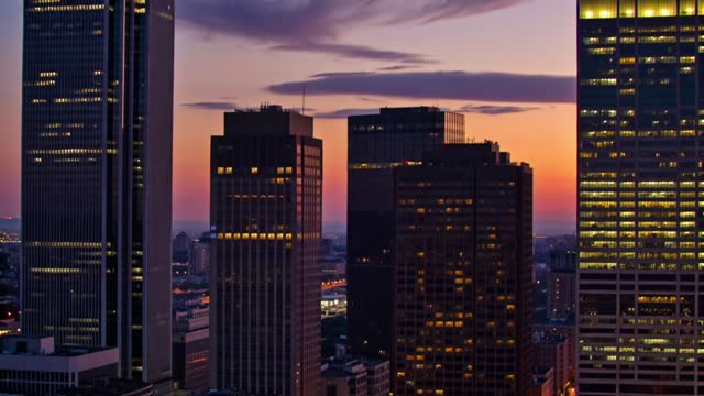 city skyline at dusk, slow camera tilt up, glowing windows and passing clouds