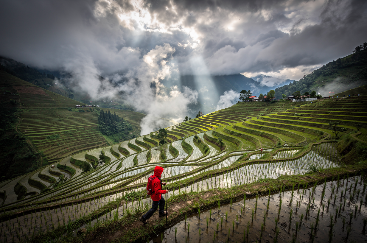 Example: Storm light over a terraced rice valley after rain, low clouds drifting through,