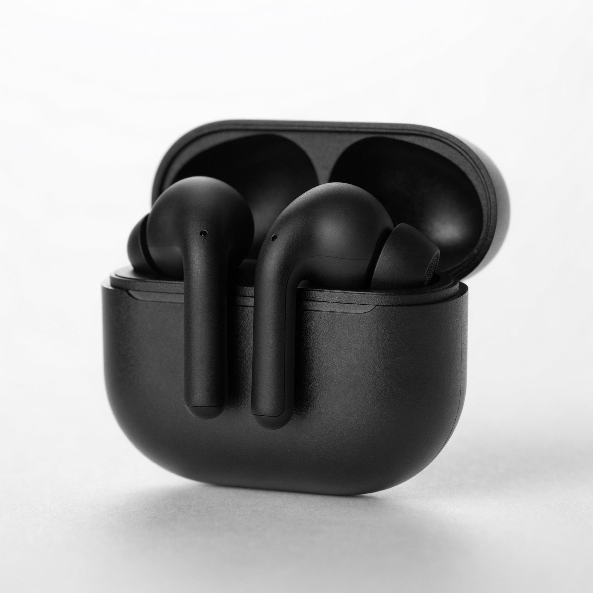 Example: Studio product photograph of matte black wireless earbuds in an open charging ca