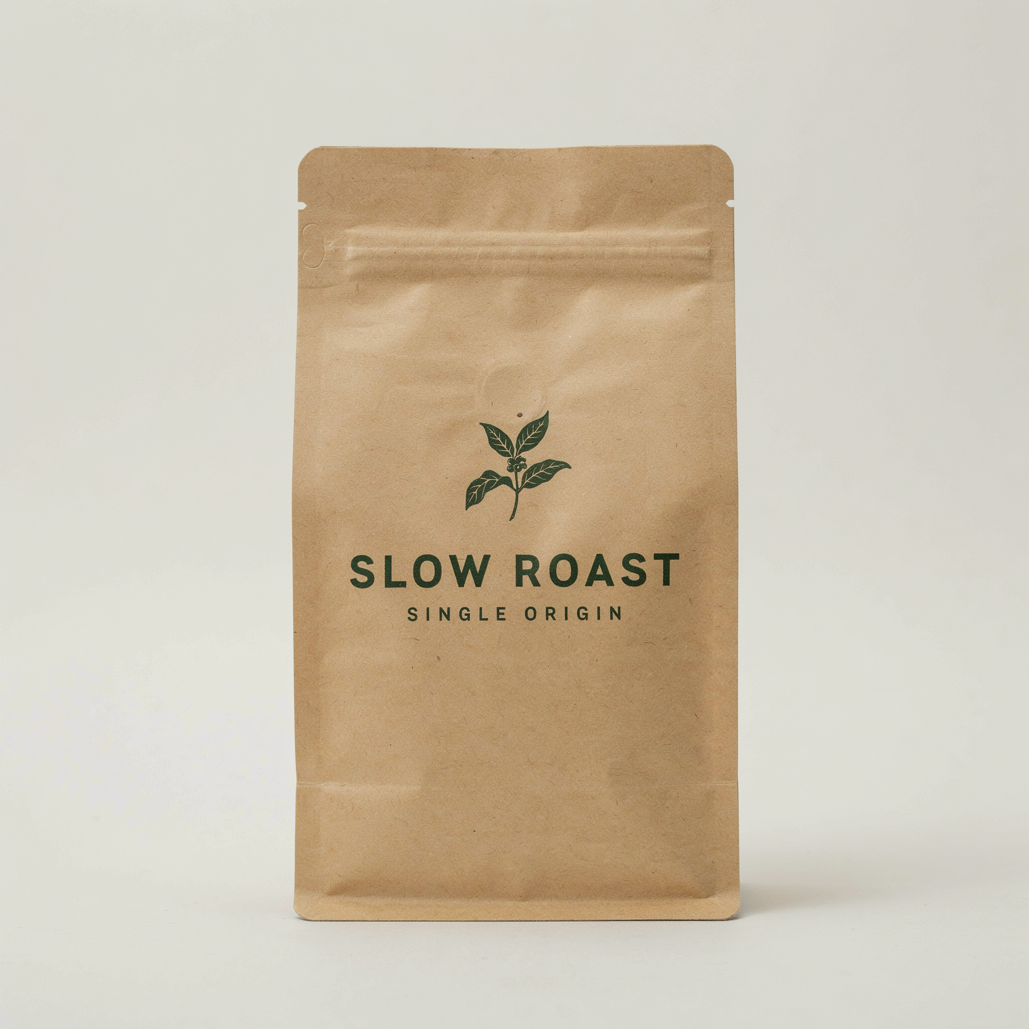 Minimal packaging design for a coffee bag labeled "SLOW ROAST", kraft paper texture, single dark green ink, small caps subtitle reading "single origin", studio product photo on a light backdrop