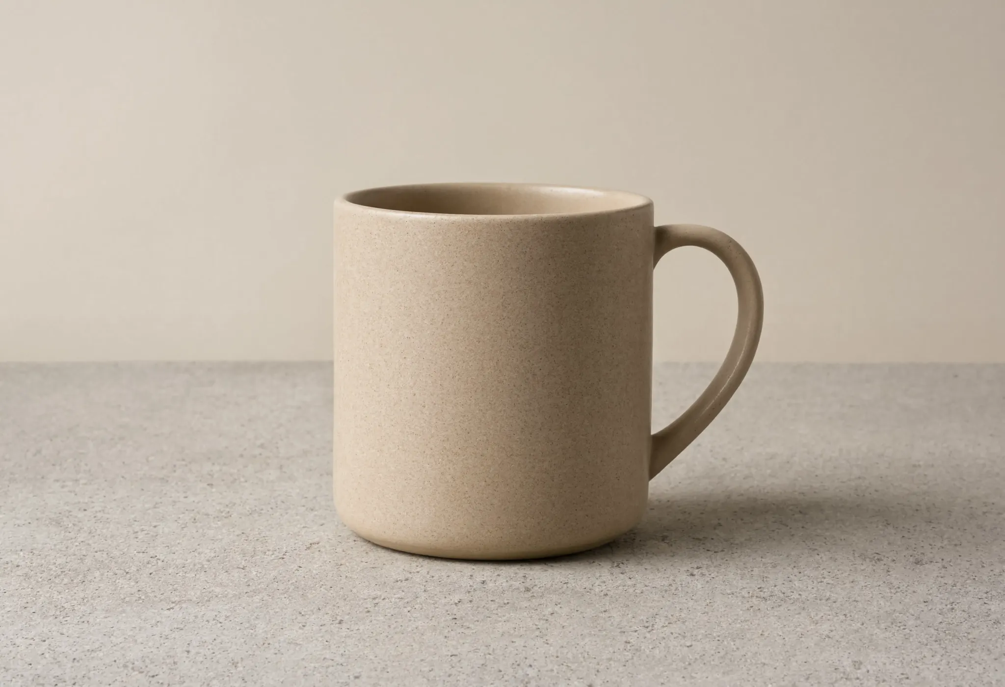 A minimalist product shot of a matte ceramic coffee mug on a concrete surface, soft studio lighting, subtle shadow, clean background