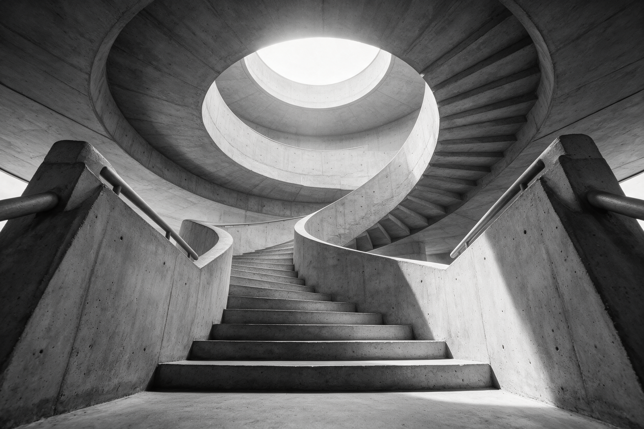 Architectural photograph of a spiral concrete staircase shot from below, daylight pouring through a circular skylight, brutalist geometry, black and white