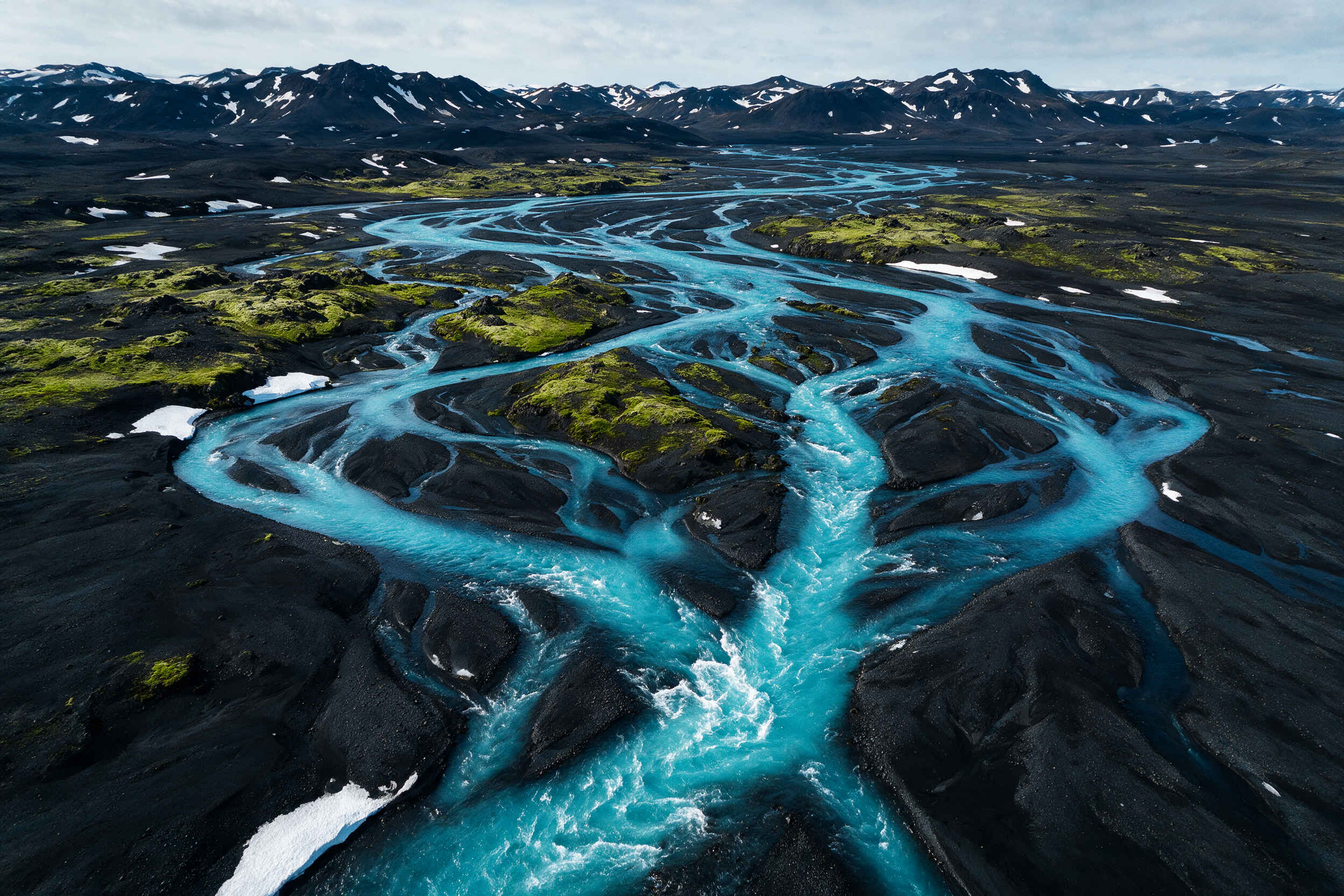 Aerial drone shot of turquoise river braids weaving through a black volcanic delta in Iceland, abstract natural patterns, high contrast, photoreal