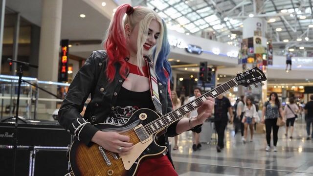 AI-generated image: Harly Quinn, plays the guitar in a "Allan Holdsworth" legeto jazz fusion style in a mall.