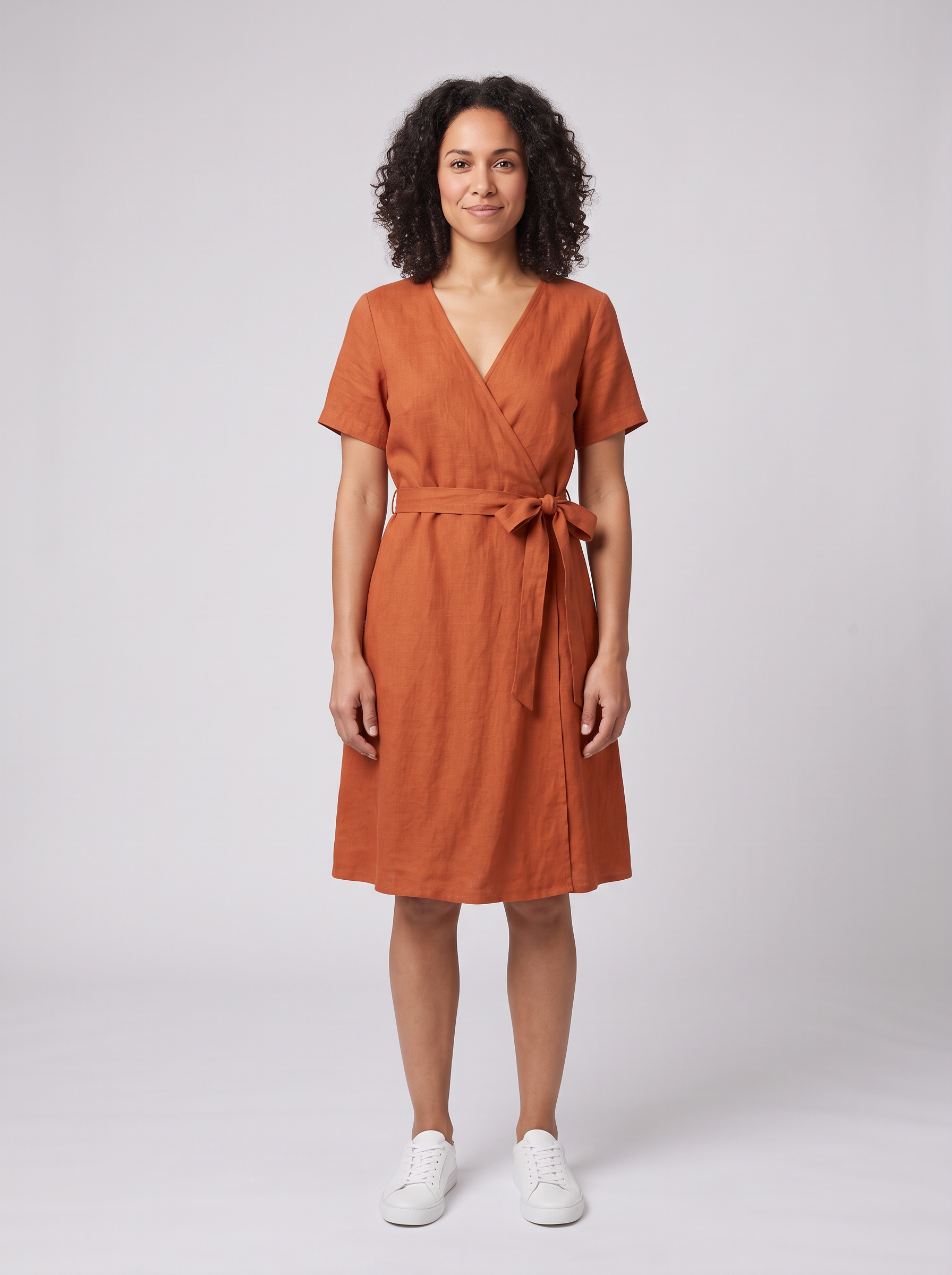 Nano Banana 2.1: the woman in the rust wrap dress with a crisp bow at the waist, sneakers and pose unchanged