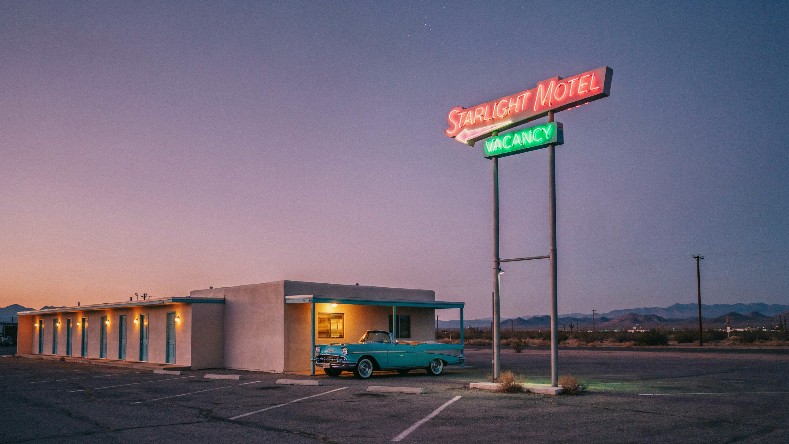 Ideogram 4 Quality: a pink neon STARLIGHT MOTEL sign with an arrow and a green VACANCY box on a tall double pole, a long pale motel block with lamplit doors and a turquoise convertible under a lilac dusk sky