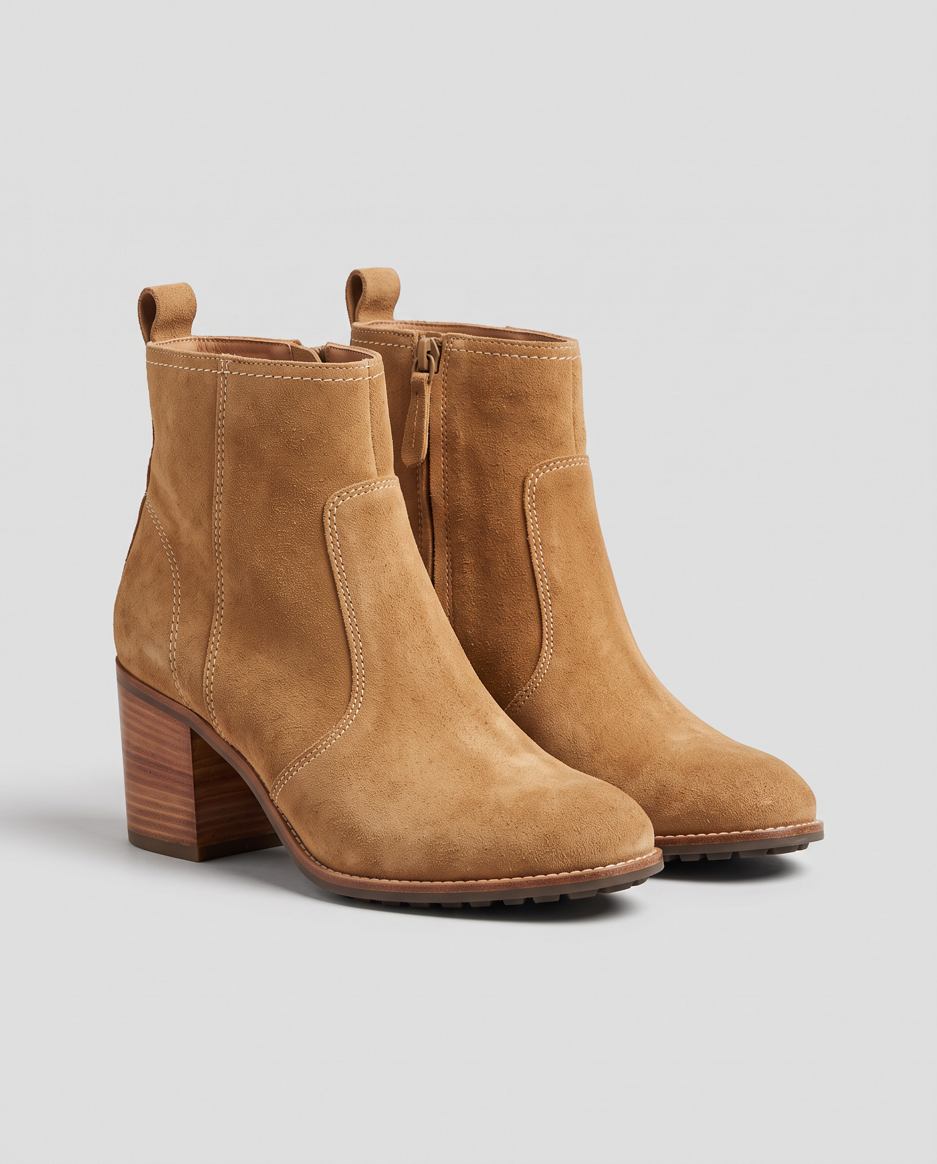 The source: tan suede ankle boots with stacked wooden heels on a plain light grey studio background
